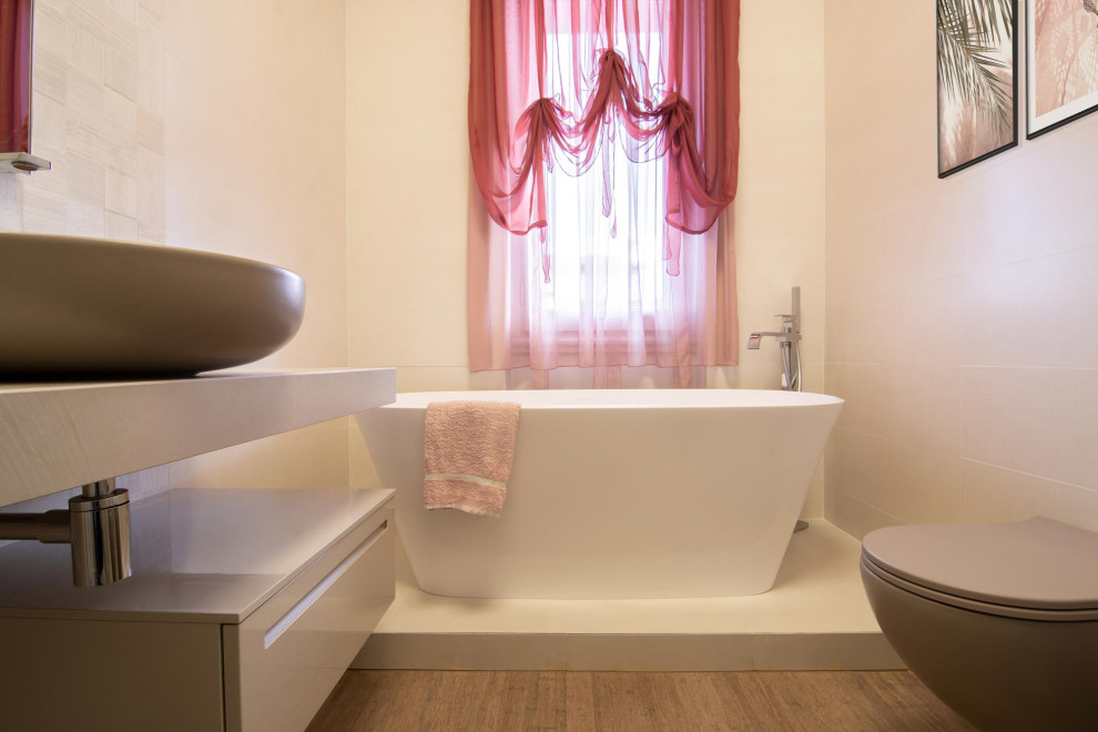 Свежая идея для дизайна: огромная ванная комната в стиле модернизм с плоскими фасадами, бежевыми фасадами, отдельно стоящей ванной, угловым душем, инсталляцией, белой плиткой, керамогранитной плиткой, бежевыми стенами, полом из бамбука, душевой кабиной, настольной раковиной, столешницей из гранита, коричневым полом, душем с раздвижными дверями, белой столешницей, тумбой под одну раковину и подвесной тумбой - отличное фото интерьера