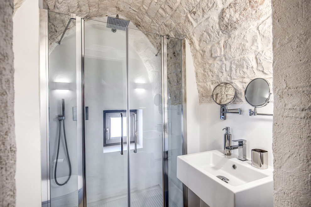 Idéer för att renovera ett medelhavsstil badrum, med en dusch i en alkov, vita väggar, ett väggmonterat handfat och dusch med gångjärnsdörr