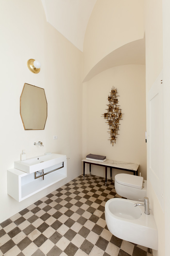 50 tals inredning av ett badrum, med öppna hyllor, vita skåp, en vägghängd toalettstol, vita väggar och ett avlångt handfat