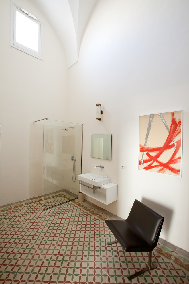 Foto på ett mellanstort medelhavsstil badrum med dusch, med öppna hyllor, vita skåp, en kantlös dusch, en vägghängd toalettstol, vita väggar, ett väggmonterat handfat och med dusch som är öppen