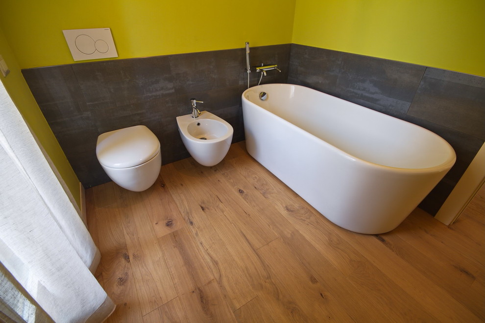 Kleines Modernes Badezimmer mit freistehender Badewanne, Wandtoilette, schwarzen Fliesen, Schieferfliesen, grüner Wandfarbe, braunem Holzboden und braunem Boden in Sonstige