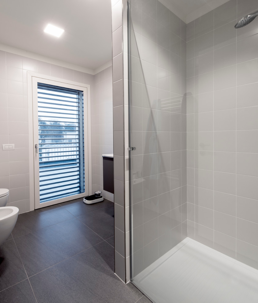 Ispirazione per una stanza da bagno minimal di medie dimensioni con WC sospeso, piastrelle grigie, piastrelle in gres porcellanato, pareti bianche, pavimento in gres porcellanato e lavabo integrato