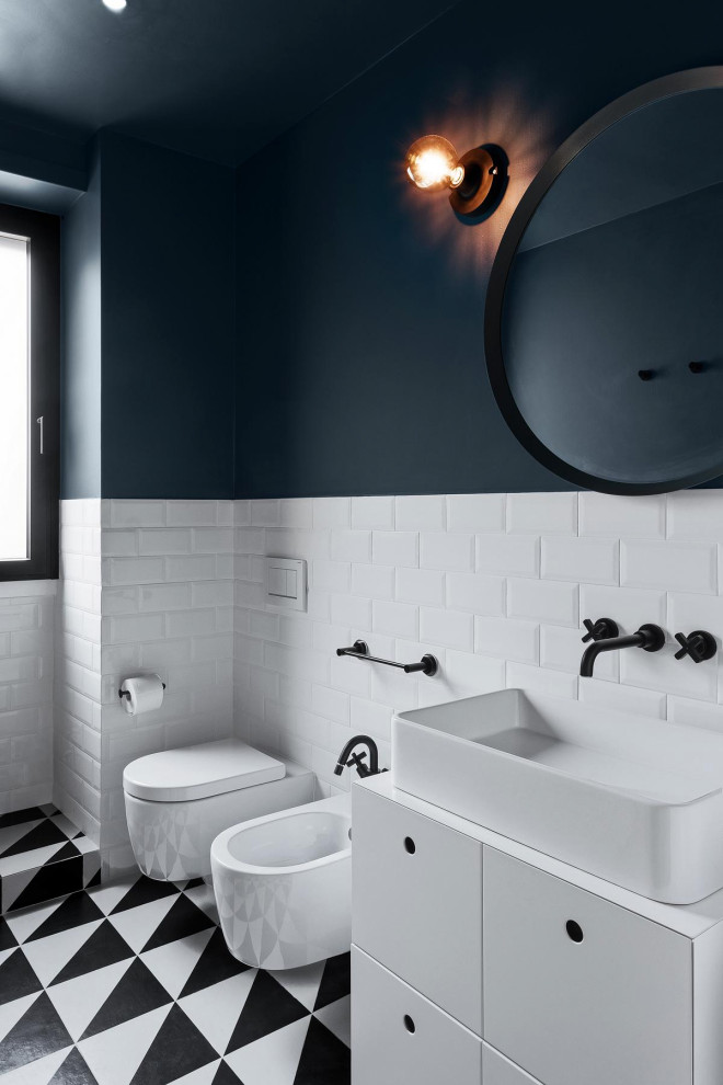 Foto på ett stort funkis vit badrum, med släta luckor, vita skåp, en bidé, vit kakel, tunnelbanekakel, svarta väggar, ett fristående handfat och flerfärgat golv