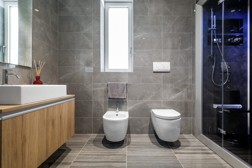 Ejemplo de cuarto de baño minimalista de tamaño medio con baldosas y/o azulejos grises, baldosas y/o azulejos de porcelana, paredes grises, suelo de baldosas de porcelana, aseo y ducha y suelo gris