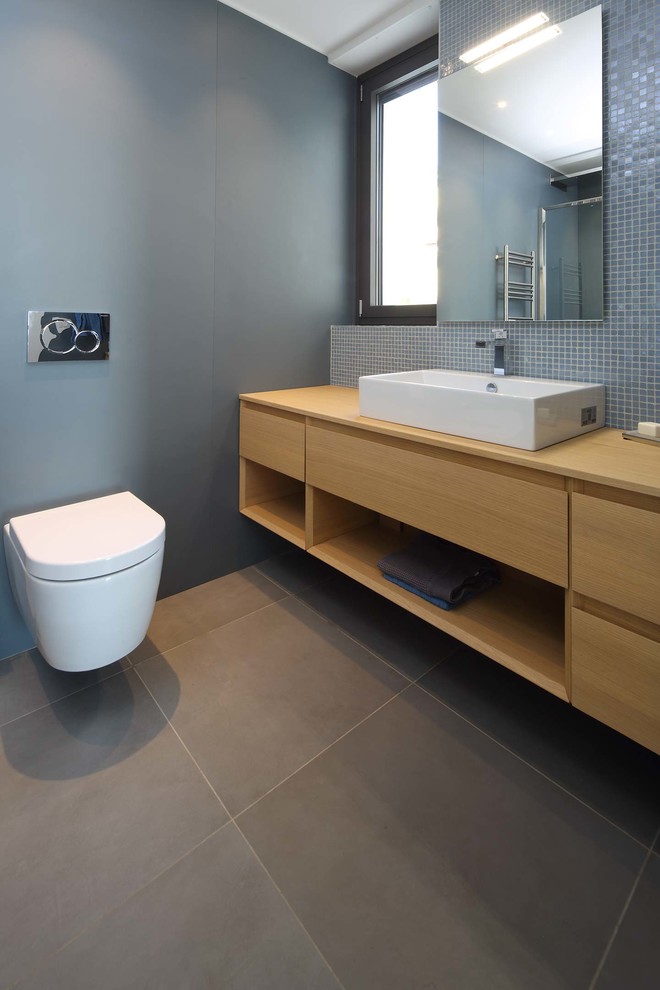 На фото: ванная комната с светлыми деревянными фасадами, инсталляцией, синей плиткой, плиткой мозаикой, синими стенами, полом из керамогранита, коричневым полом и коричневой столешницей