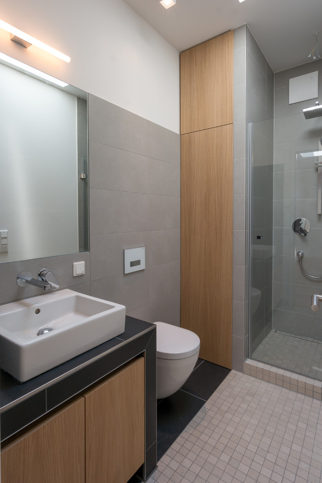 Modernes Badezimmer mit hellbraunen Holzschränken, bodengleicher Dusche, grauen Fliesen, Mosaikfliesen, weißer Wandfarbe und Mosaik-Bodenfliesen in Berlin