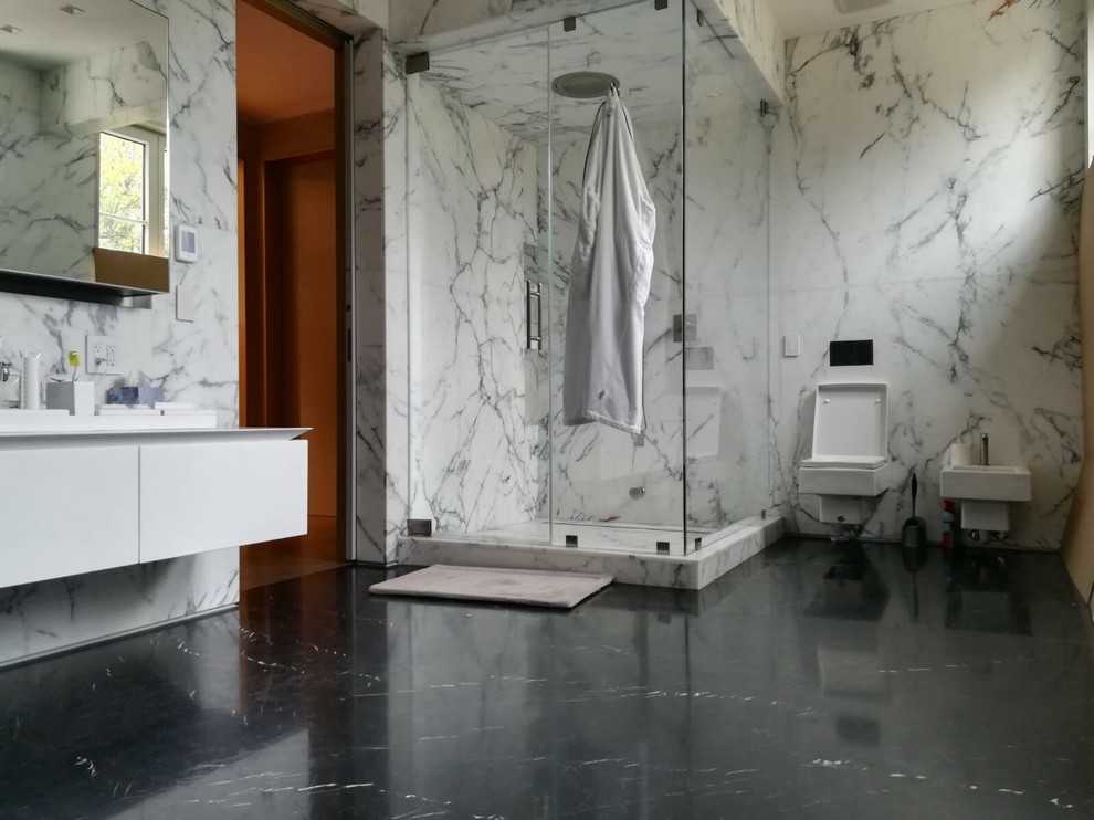 Foto di una stanza da bagno con doccia contemporanea con doccia ad angolo, WC a due pezzi, piastrelle bianche, piastrelle di marmo, pareti bianche, pavimento in marmo, pavimento nero e porta doccia a battente