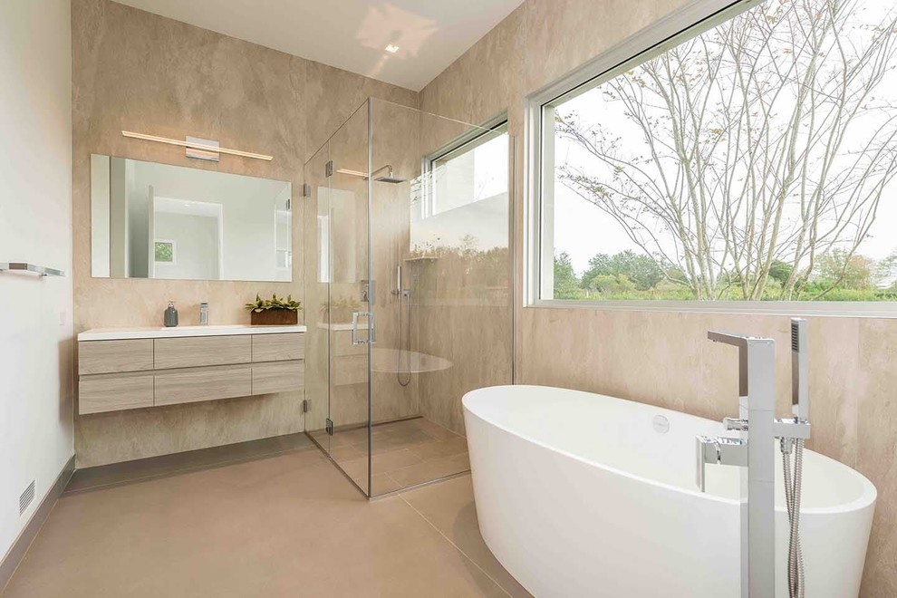 Bild på ett funkis vit vitt badrum, med brun kakel, porslinskakel, beige väggar, klinkergolv i porslin, beiget golv, släta luckor, skåp i ljust trä, ett fristående badkar, en hörndusch och dusch med gångjärnsdörr