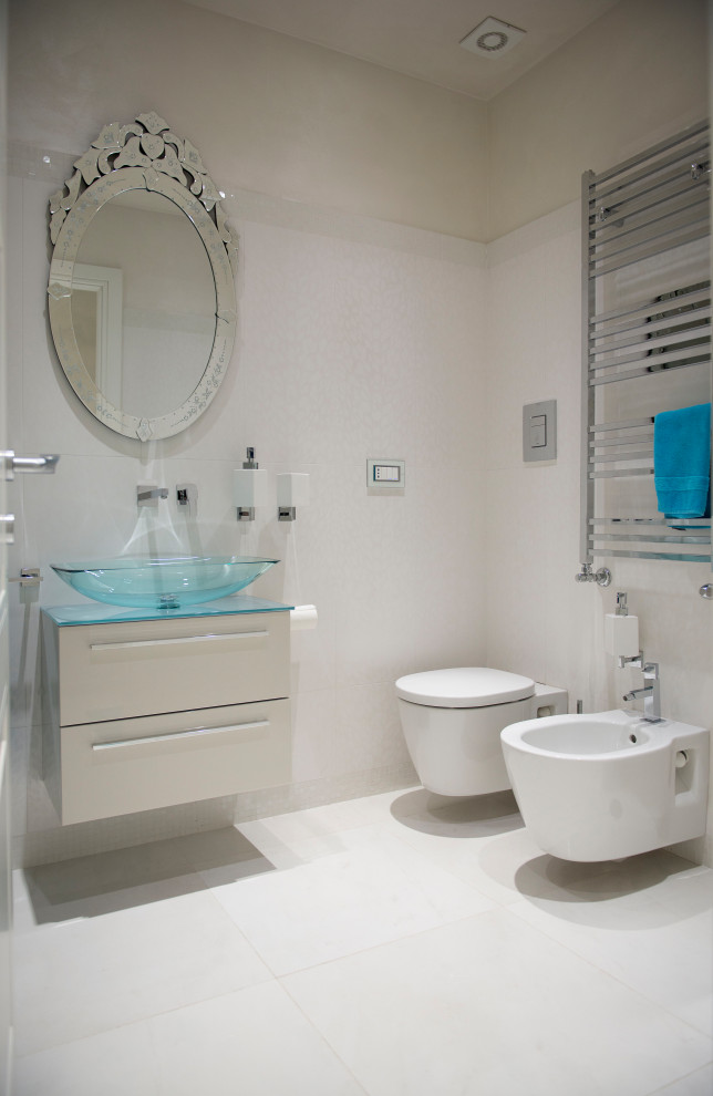 На фото: ванная комната среднего размера в современном стиле с плоскими фасадами, бежевыми фасадами, инсталляцией, белой плиткой, бежевыми стенами, душевой кабиной, настольной раковиной, стеклянной столешницей, белым полом и синей столешницей с