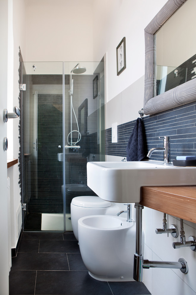 Kleines Modernes Duschbad mit hellen Holzschränken, bodengleicher Dusche, grauen Fliesen, Porzellanfliesen, Porzellan-Bodenfliesen, Waschtisch aus Holz und brauner Waschtischplatte in Mailand