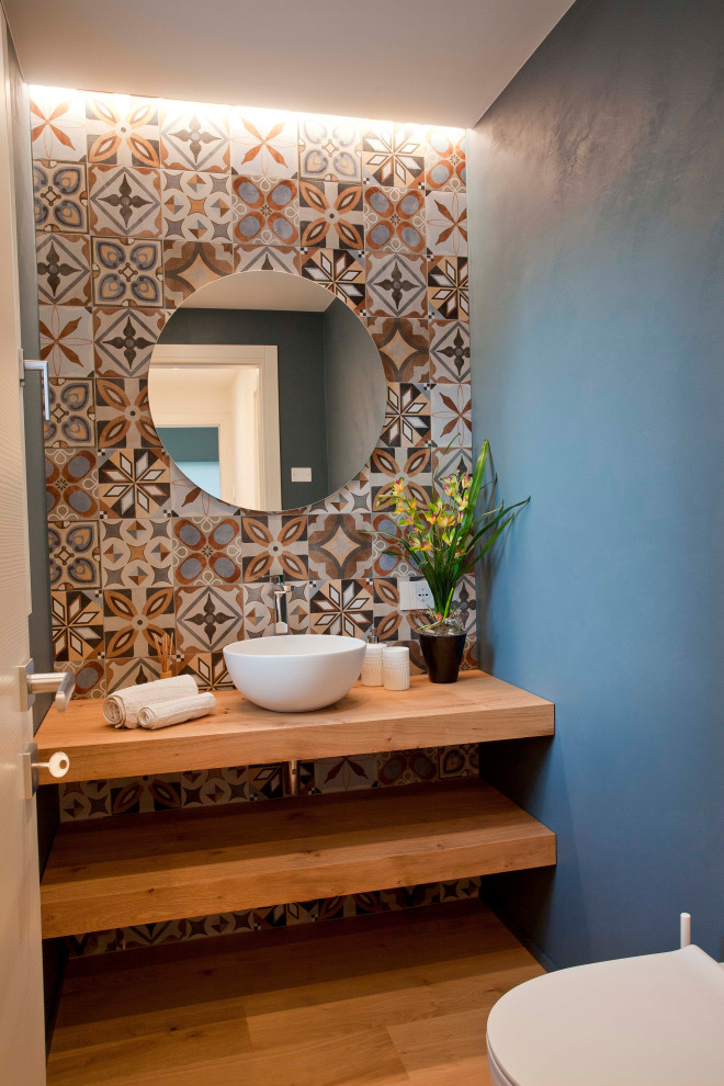 Bild på ett litet funkis badrum, med skåp i ljust trä, flerfärgad kakel, träbänkskiva, blå väggar och laminatgolv