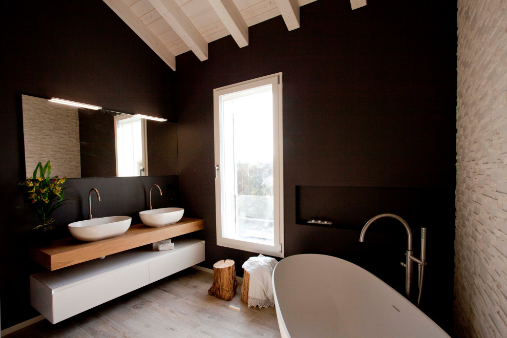 Идея дизайна: огромная главная ванная комната в современном стиле с открытыми фасадами, белыми фасадами, отдельно стоящей ванной, открытым душем, удлиненной плиткой, серыми стенами, настольной раковиной, столешницей из дерева и открытым душем
