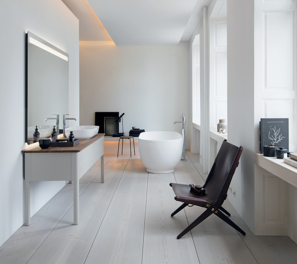 Пример оригинального дизайна: большая главная ванная комната в современном стиле с отдельно стоящей ванной, белыми стенами, деревянным полом, настольной раковиной, столешницей из дерева и белым полом