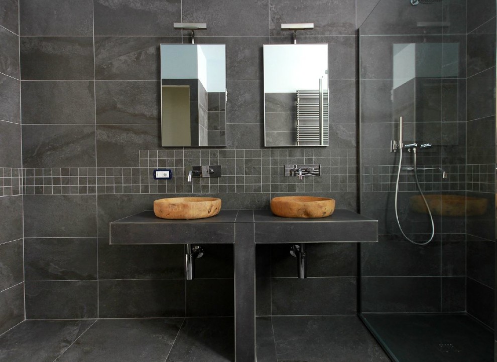 Bild på ett funkis badrum med dusch, med en hörndusch, svart kakel, stenhäll och ett fristående handfat