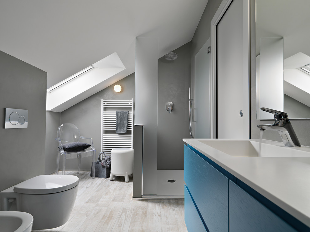 На фото: маленькая главная ванная комната в стиле модернизм с синими фасадами, угловым душем, инсталляцией, серой плиткой, серыми стенами, полом из керамогранита и монолитной раковиной для на участке и в саду