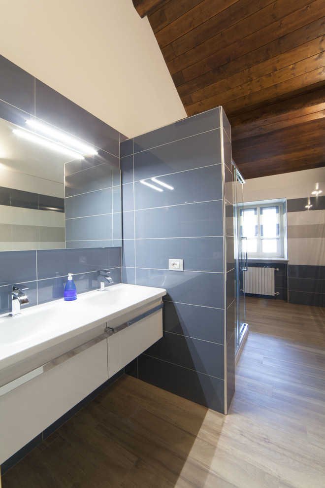 Corner shower - mid-sized modern 3/4 blue tile and porcelain tile porcelain tile corner shower idea in Milan with flat-panel cabinets, white cabinets, blue walls and a wall-mount sink