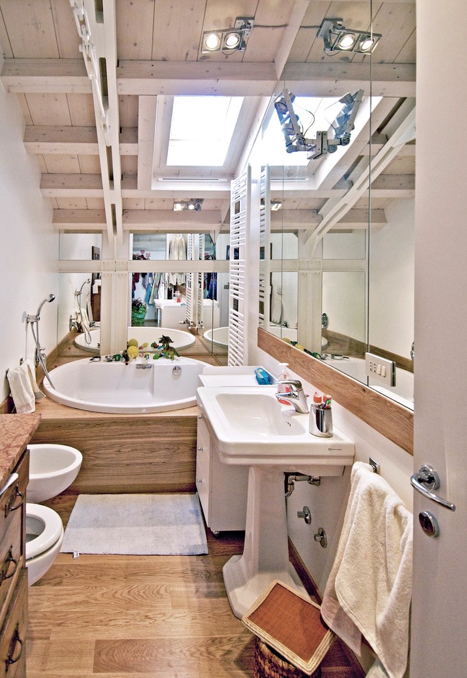Esempio di una piccola stanza da bagno padronale design con ante lisce, ante bianche, vasca da incasso, WC sospeso, pareti bianche, parquet chiaro, lavabo a colonna e pavimento marrone