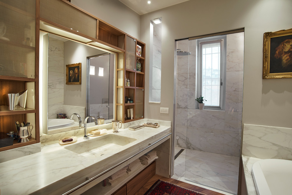 Идея дизайна: огромная главная ванная комната в стиле неоклассика (современная классика) с накладной ванной, душем без бортиков, унитазом-моноблоком, белой плиткой, мраморной плиткой, бежевыми стенами, паркетным полом среднего тона, монолитной раковиной, мраморной столешницей, коричневым полом, душем с раздвижными дверями, белой столешницей, фасадами цвета дерева среднего тона и плоскими фасадами