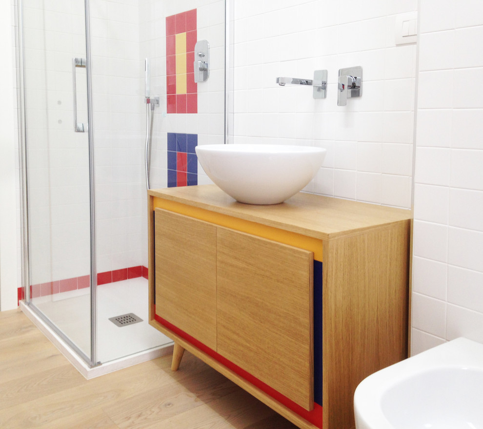Inspiration for a small modern bathroom in Bologna with glass-front cabinets, light wood cabinets, a one-piece toilet, multi-coloured tiles, ceramic tiles, multi-coloured walls, light hardwood flooring, a vessel sink and wooden worktops.