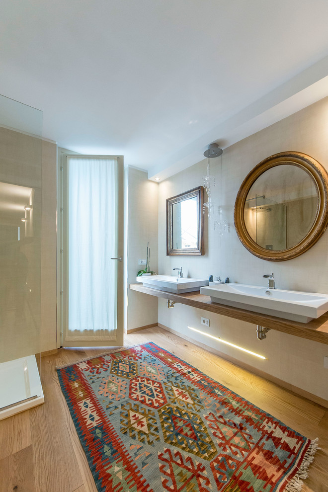 Eclectic master beige tile medium tone wood floor and beige floor bathroom photo in Other with a wall-mount toilet, beige walls, a console sink, wood countertops and brown countertops
