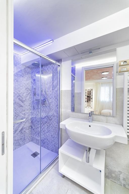 Пример оригинального дизайна: маленькая ванная комната в современном стиле с открытыми фасадами, белыми фасадами, душем без бортиков, раздельным унитазом, разноцветной плиткой, плиткой мозаикой, белыми стенами, душевой кабиной, подвесной раковиной, белым полом, душем с раздвижными дверями и полом из керамогранита для на участке и в саду