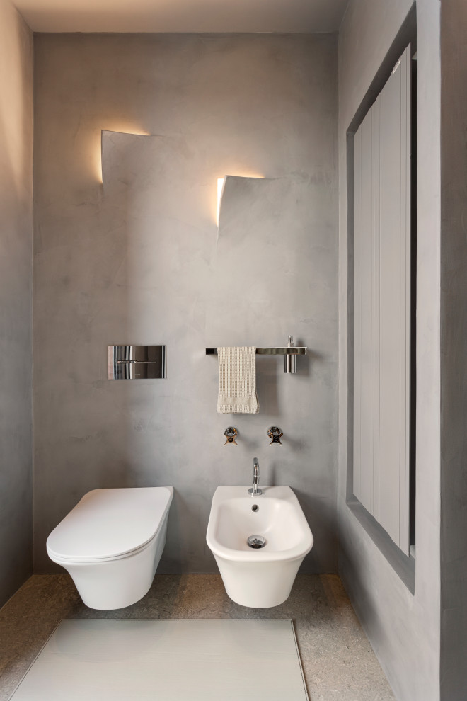 Foto på ett mellanstort funkis vit badrum med dusch, med släta luckor, vita skåp, en dusch i en alkov, en vägghängd toalettstol, grå kakel, grå väggar, kalkstensgolv, ett integrerad handfat, bänkskiva i glas, grått golv och dusch med gångjärnsdörr
