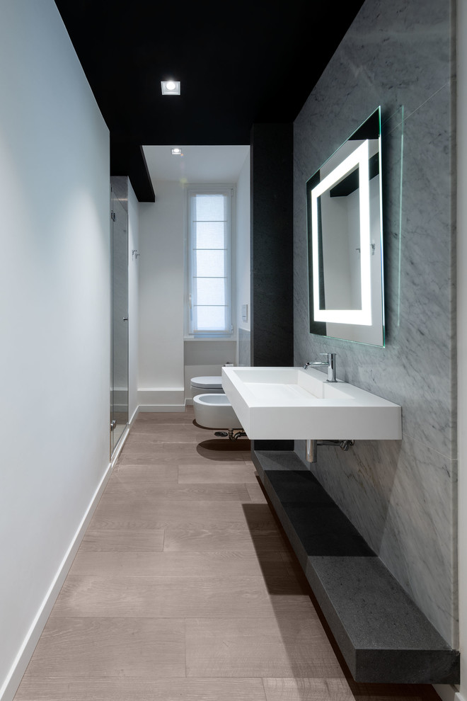 Inspiration för mellanstora moderna vitt badrum med dusch, med öppna hyllor, en dusch i en alkov, grå kakel, stenhäll, vita väggar, ett väggmonterat handfat, bänkskiva i akrylsten, dusch med gångjärnsdörr, en bidé och brunt golv