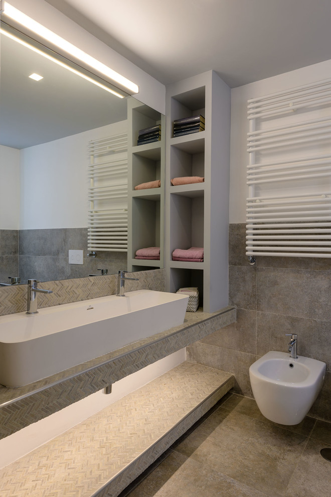 Inspiration för stora moderna en-suite badrum, med öppna hyllor, grå skåp, ett fristående badkar, en vägghängd toalettstol, grå kakel, porslinskakel, grå väggar, klinkergolv i porslin, ett fristående handfat, bänkskiva i kalksten och grått golv