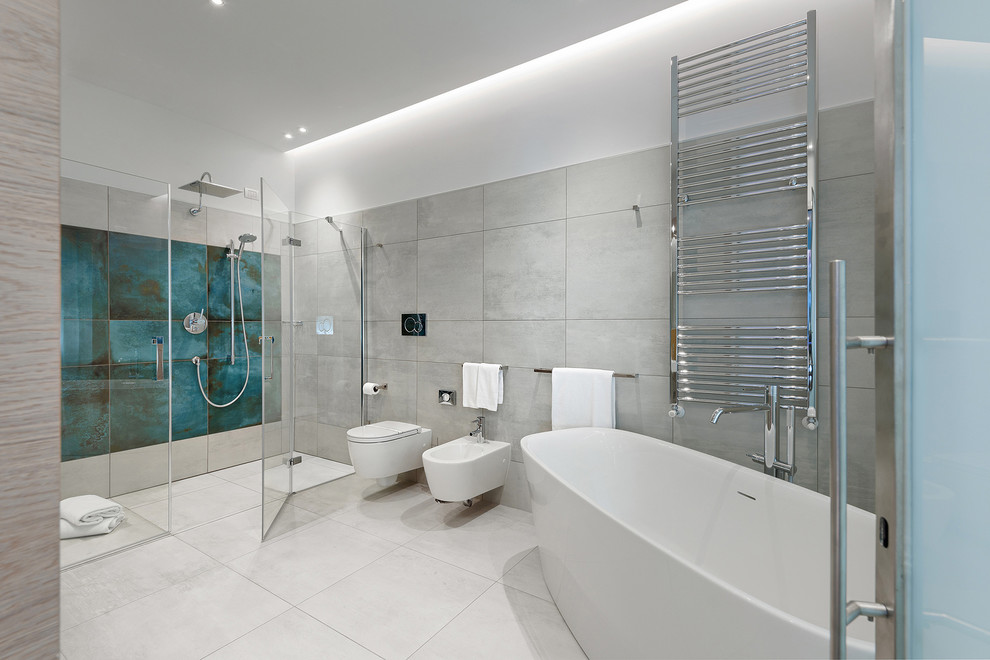 Photo of a large contemporary shower room bathroom with flat-panel cabinets, a freestanding bath, a double shower, a two-piece toilet, grey tiles, porcelain tiles, grey walls, porcelain flooring, a built-in sink, grey floors and a hinged door.