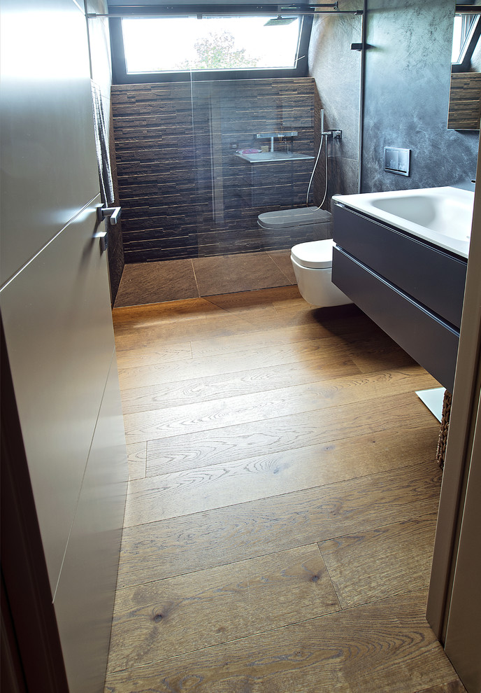 Immagine di una piccola stanza da bagno con doccia moderna con ante lisce, ante marroni, doccia a filo pavimento, lastra di pietra, parquet chiaro e lavabo da incasso