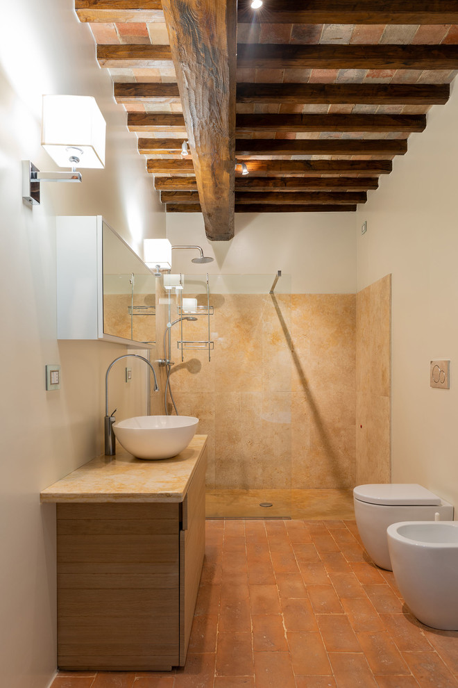 Inspiration for a large rural shower room bathroom in Other with flat-panel cabinets, light wood cabinets, a built-in shower, a two-piece toilet, beige tiles, stone slabs, white walls, terracotta flooring, a vessel sink, marble worktops, an open shower and beige worktops.
