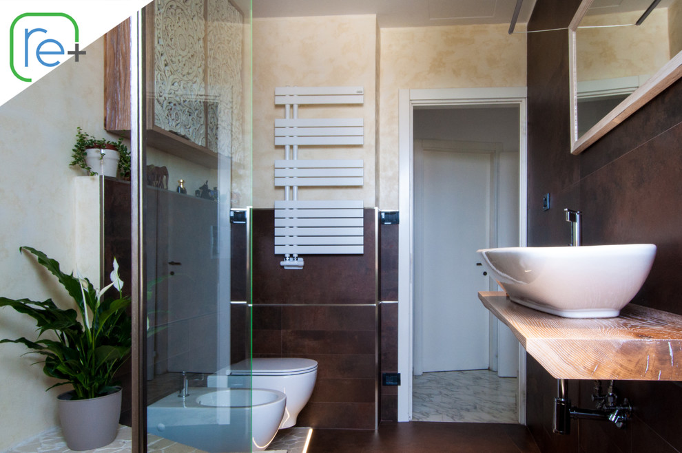 This is an example of a large modern ensuite bathroom in Other with open cabinets, light wood cabinets, a built-in bath, a shower/bath combination, a wall mounted toilet, brown tiles, porcelain tiles, beige walls, marble flooring, a vessel sink, wooden worktops, beige floors, an open shower and brown worktops.