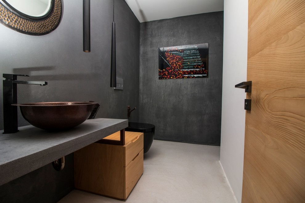 Cette image montre une petite salle de bain design avec un mur noir, sol en béton ciré, un plan de toilette en béton, un sol gris et un plan de toilette gris.