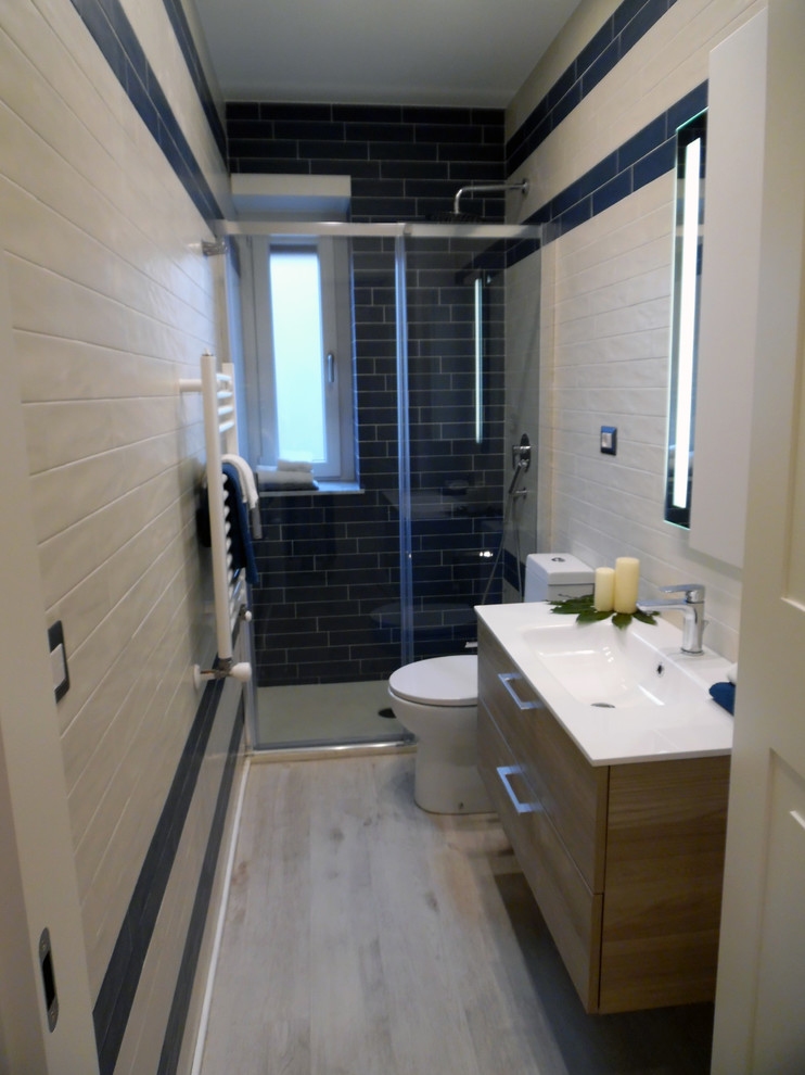 Пример оригинального дизайна: маленькая ванная комната в современном стиле с плоскими фасадами, светлыми деревянными фасадами, унитазом-моноблоком, разноцветной плиткой, керамогранитной плиткой, разноцветными стенами, полом из винила, душевой кабиной, консольной раковиной, бежевым полом и душем с раздвижными дверями для на участке и в саду
