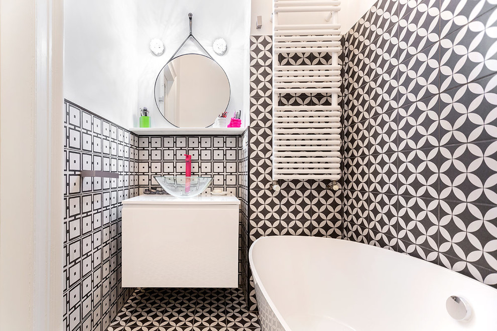 Inspiration pour une salle de bain design avec un placard à porte plane, des portes de placard blanches, une baignoire indépendante, un carrelage noir et blanc, un mur blanc, une vasque, un sol multicolore et un plan de toilette blanc.