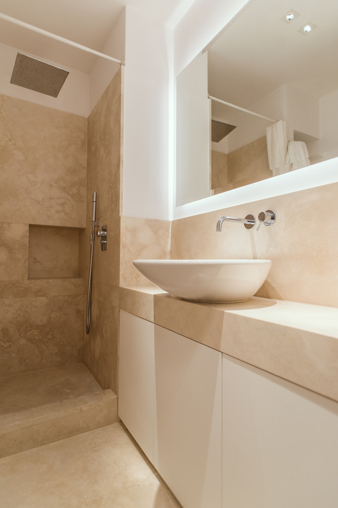 Inredning av ett modernt mellanstort beige beige badrum med dusch, med släta luckor, vita skåp, en kantlös dusch, beige kakel, travertinkakel, vita väggar, marmorgolv, ett fristående handfat och beiget golv