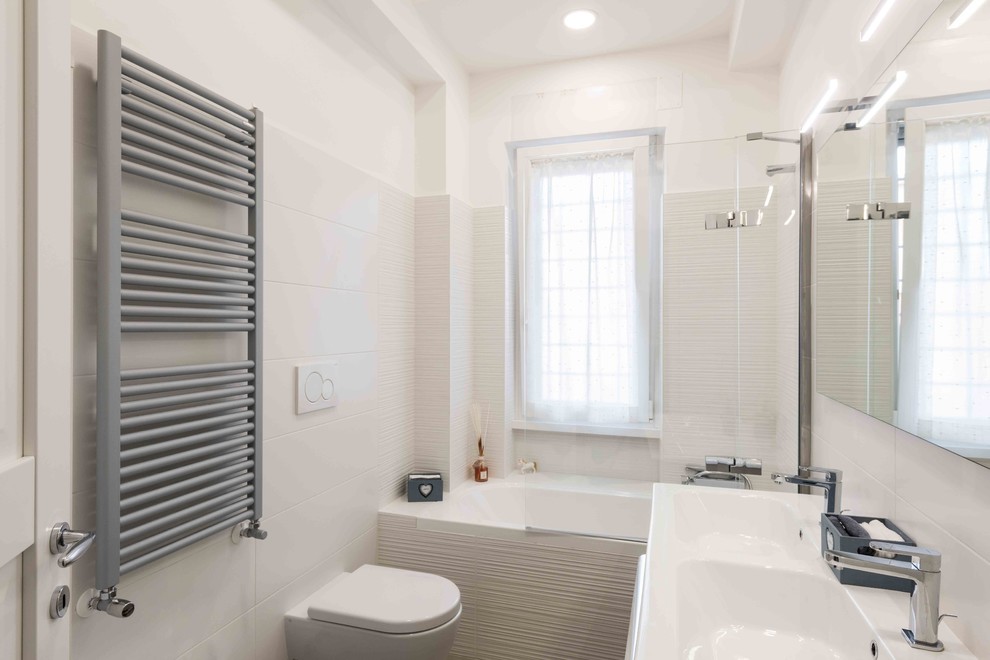 Modernes Badezimmer En Suite mit Eckbadewanne, Wandtoilette mit Spülkasten, weißen Fliesen, Porzellanfliesen, weißer Wandfarbe, Porzellan-Bodenfliesen, integriertem Waschbecken und grauem Boden in Rom