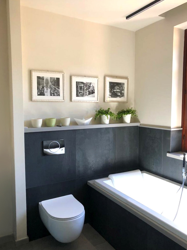 Small modern ensuite bathroom in Other with flat-panel cabinets, green cabinets, a built-in bath, black tiles, porcelain tiles, white walls, porcelain flooring, an integrated sink, engineered stone worktops, grey floors, white worktops and a two-piece toilet.