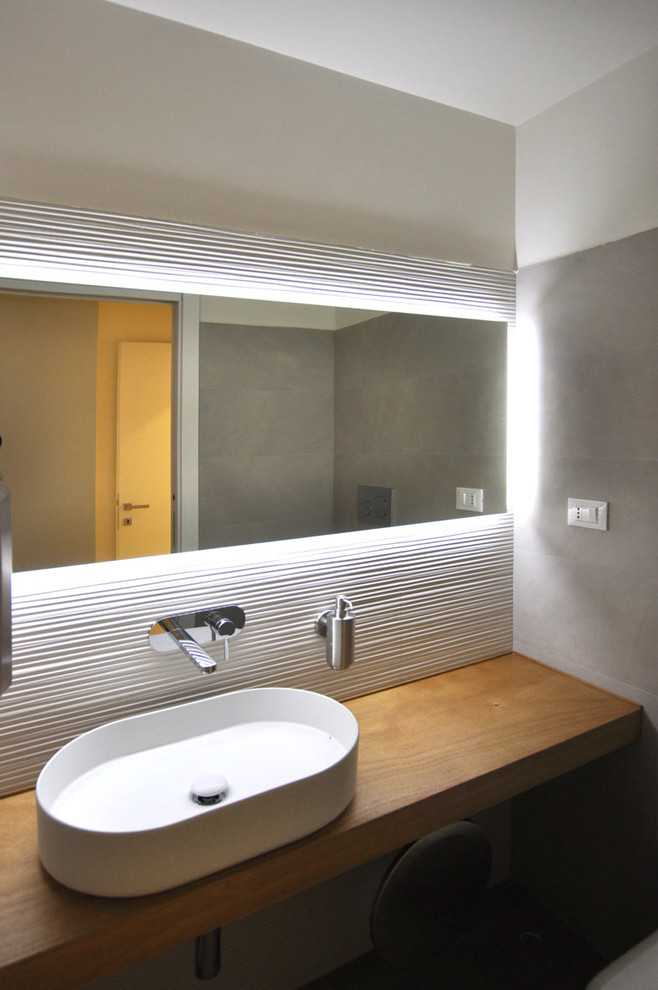 Inredning av ett modernt litet en-suite badrum, med skåp i ljust trä, vit kakel, träbänkskiva, en vägghängd toalettstol, porslinskakel, beige väggar, klinkergolv i porslin, ett fristående handfat och brunt golv
