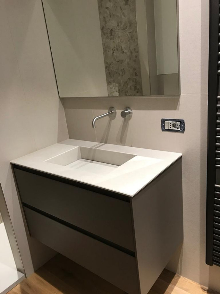 Modern inredning av ett litet badrum med dusch, med släta luckor, beige skåp, en toalettstol med separat cisternkåpa, beige kakel, porslinskakel, beige väggar, mellanmörkt trägolv och ett integrerad handfat