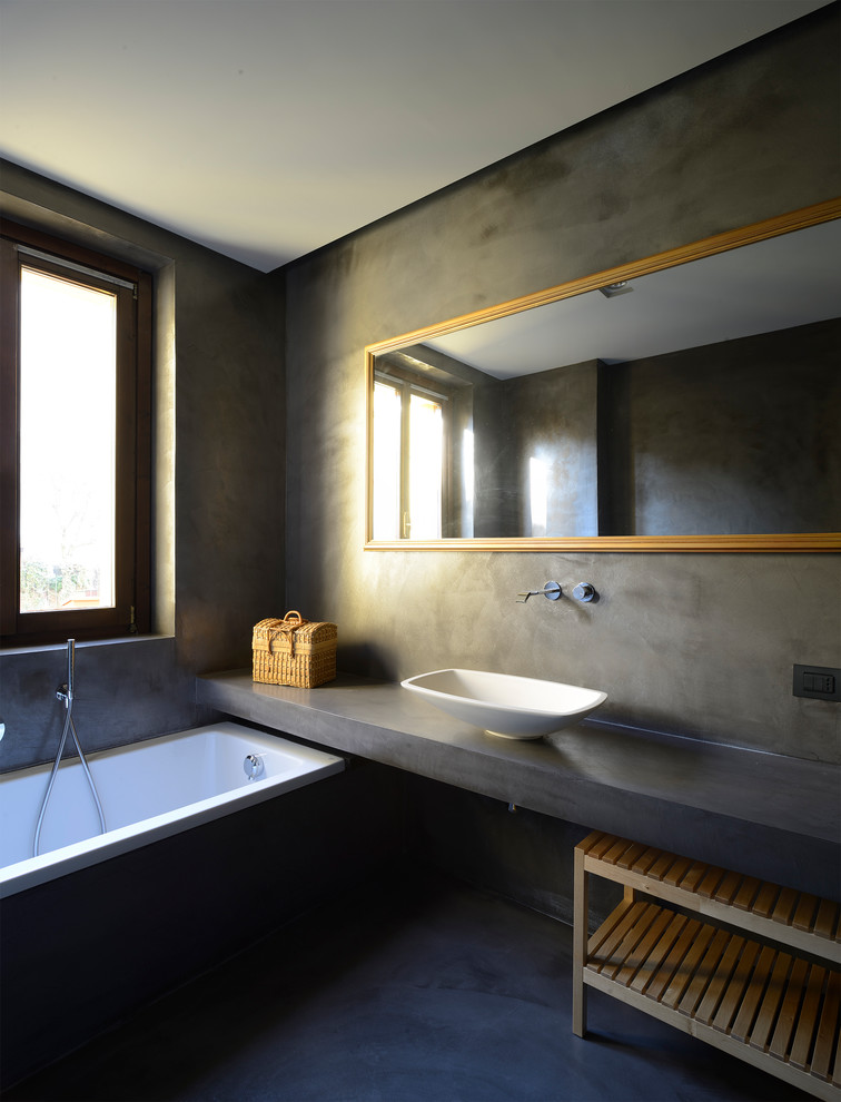 Inredning av ett modernt grå grått badrum, med ett platsbyggt badkar, grå väggar, ett fristående handfat och grått golv