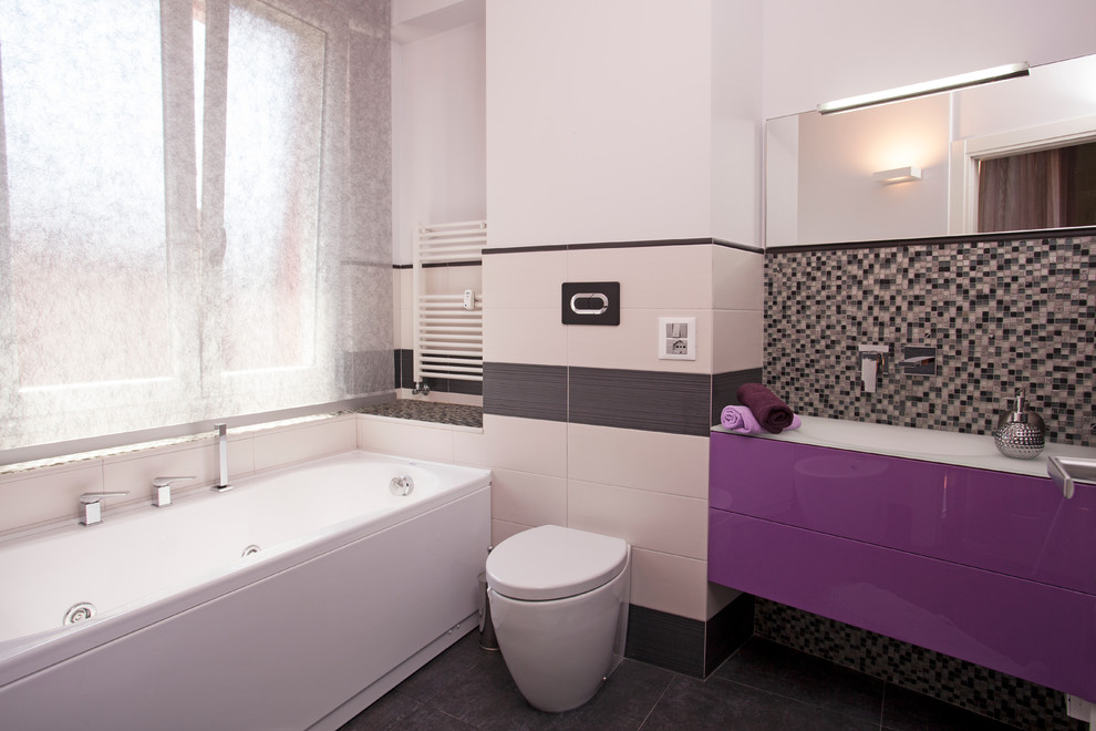 Bild på ett mellanstort funkis en-suite badrum, med släta luckor, ett fristående badkar, en toalettstol med hel cisternkåpa, svart och vit kakel och ett nedsänkt handfat