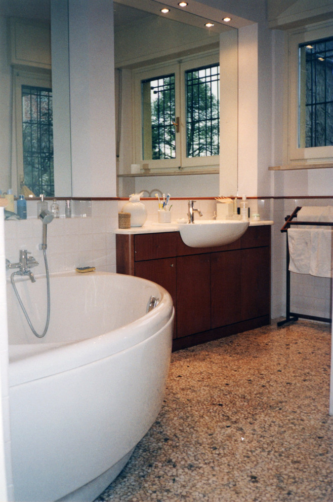 Идея дизайна: ванная комната среднего размера в стиле модернизм с плоскими фасадами, темными деревянными фасадами, угловой ванной, бежевой плиткой, керамической плиткой, бежевыми стенами, полом из галечной плитки, накладной раковиной и мраморной столешницей