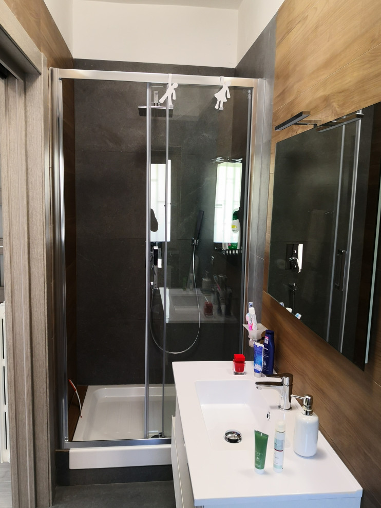 Exempel på ett mellanstort modernt vit vitt badrum med dusch, med släta luckor, vita skåp, en toalettstol med separat cisternkåpa, stenhäll, klinkergolv i porslin, ett integrerad handfat, laminatbänkskiva, grått golv och dusch med skjutdörr