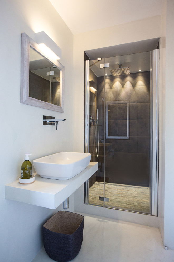Modelo de cuarto de baño contemporáneo con paredes blancas, suelo de baldosas de porcelana, lavabo sobreencimera, ducha empotrada, baldosas y/o azulejos negros y ducha con puerta con bisagras