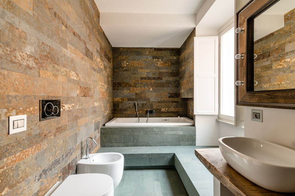 Inredning av ett rustikt en-suite badrum, med skåp i ljust trä, ett platsbyggt badkar, en bidé, bruna väggar, ett fristående handfat och träbänkskiva