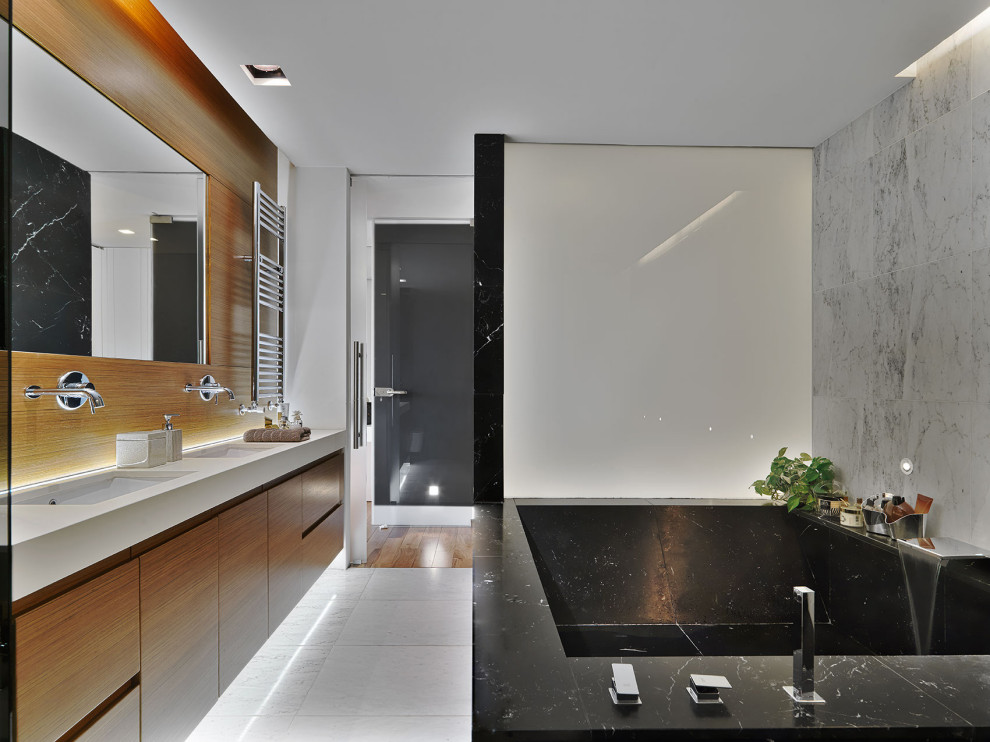 Example of a large trendy master gray tile and porcelain tile porcelain tile and gray floor corner bathtub design in Milan with flat-panel cabinets, medium tone wood cabinets, white walls, gray countertops and a floating vanity