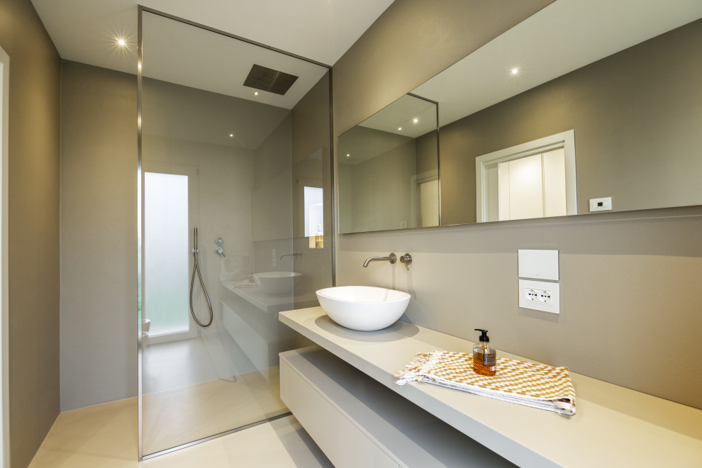 Foto de cuarto de baño moderno con armarios con paneles lisos, puertas de armario grises, ducha empotrada, paredes grises, lavabo sobreencimera, suelo gris, ducha abierta y encimeras blancas
