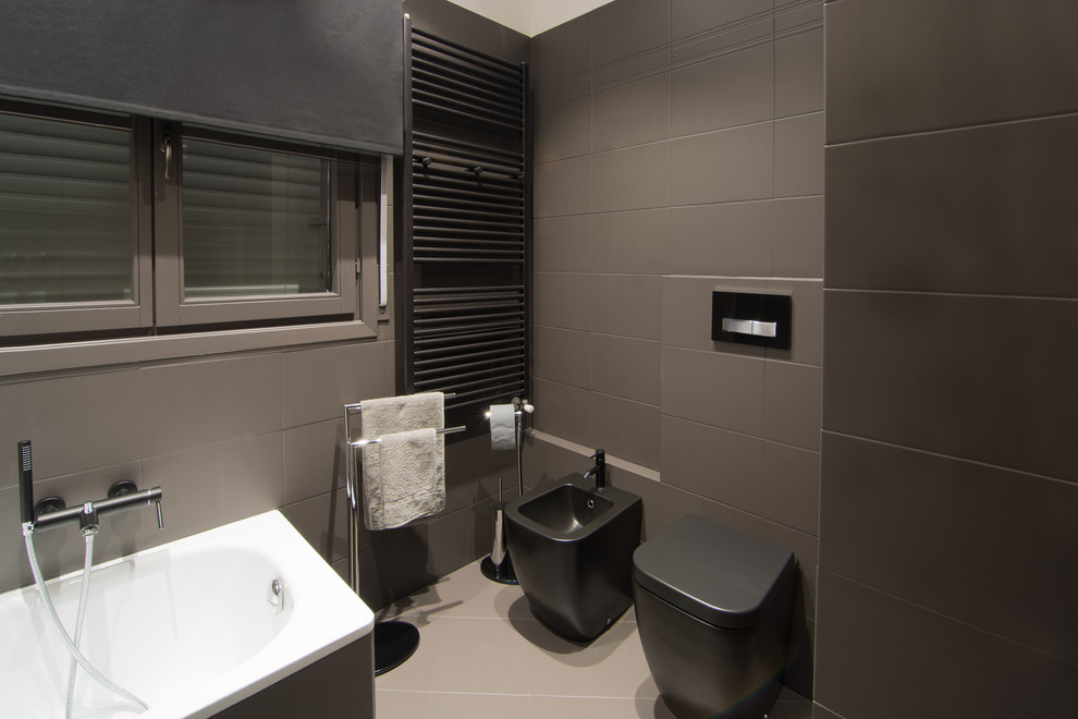 Design ideas for a medium sized contemporary ensuite bathroom in Florence with flat-panel cabinets, grey cabinets, a built-in bath, a one-piece toilet, grey tiles, ceramic tiles, grey walls, concrete flooring, an integrated sink and quartz worktops.