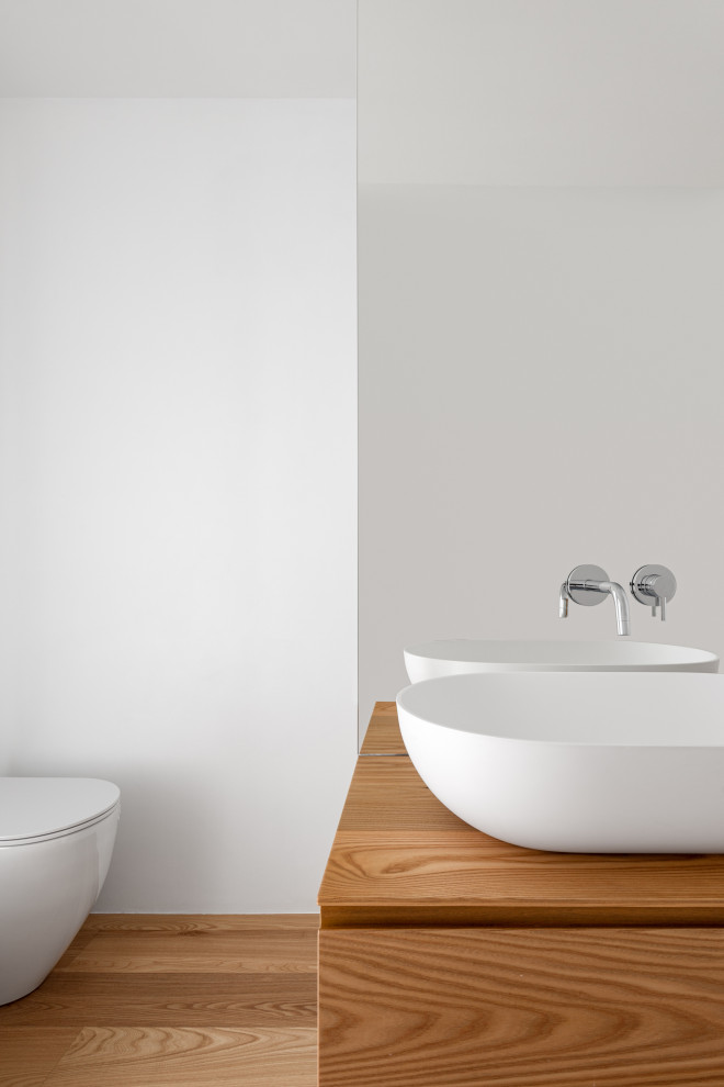 Réalisation d'une salle d'eau design en bois clair de taille moyenne avec un placard à porte affleurante, un espace douche bain, WC séparés, un carrelage blanc, des carreaux de miroir, un mur blanc, parquet clair, une vasque, un plan de toilette en surface solide, un sol beige, une cabine de douche à porte battante, un plan de toilette blanc, une niche, meuble simple vasque et meuble-lavabo suspendu.